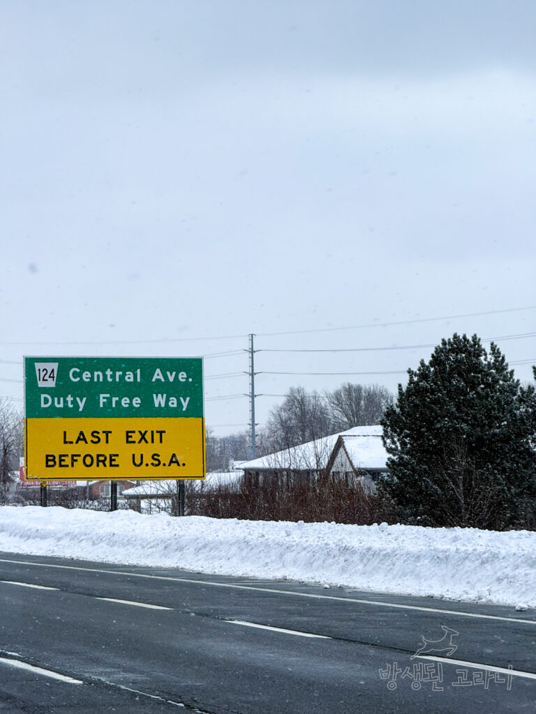 눈이 내리는 도로 위로 보이는 미국 국경 마지막 출구 이정표