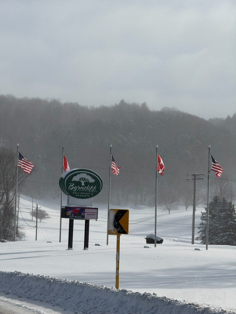 Byrncliff 골프 리조트 안내 표지판과 펄럭이는 미국과 캐나다 국기