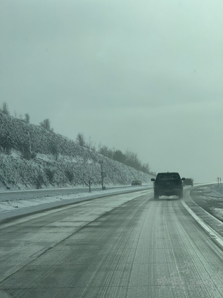 눈이 내리는 도로 위를 달리고 있는 여러 대의 차들